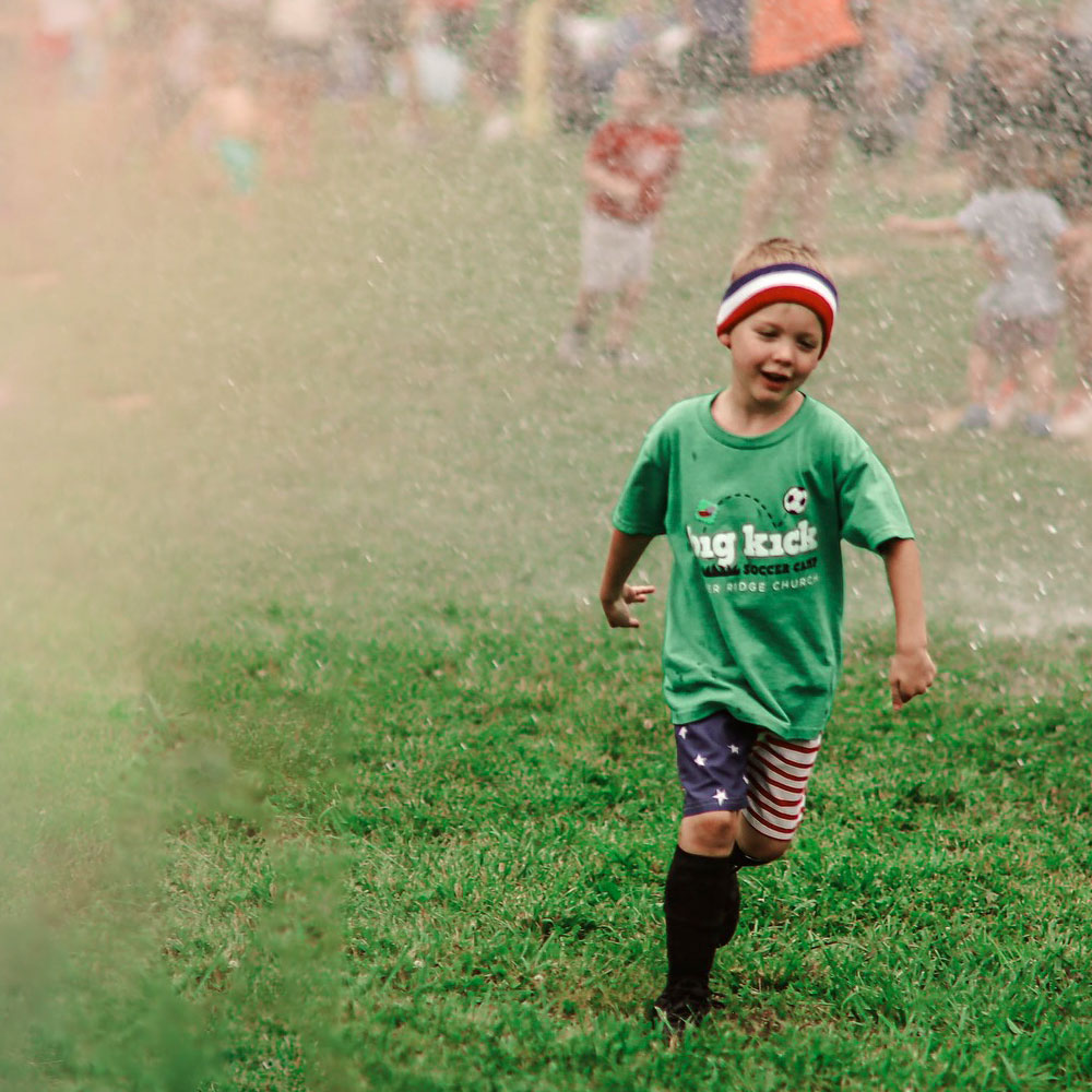 little-kid-wearing-a-Big-Kick-Soccer-shirt little kid playing soccer
